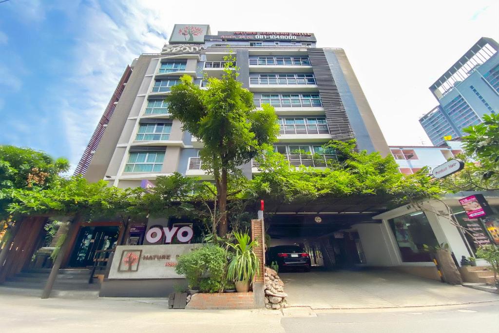 曼谷Super OYO Capital O 564 Nature Boutique Hotel的前面有一棵树的高楼