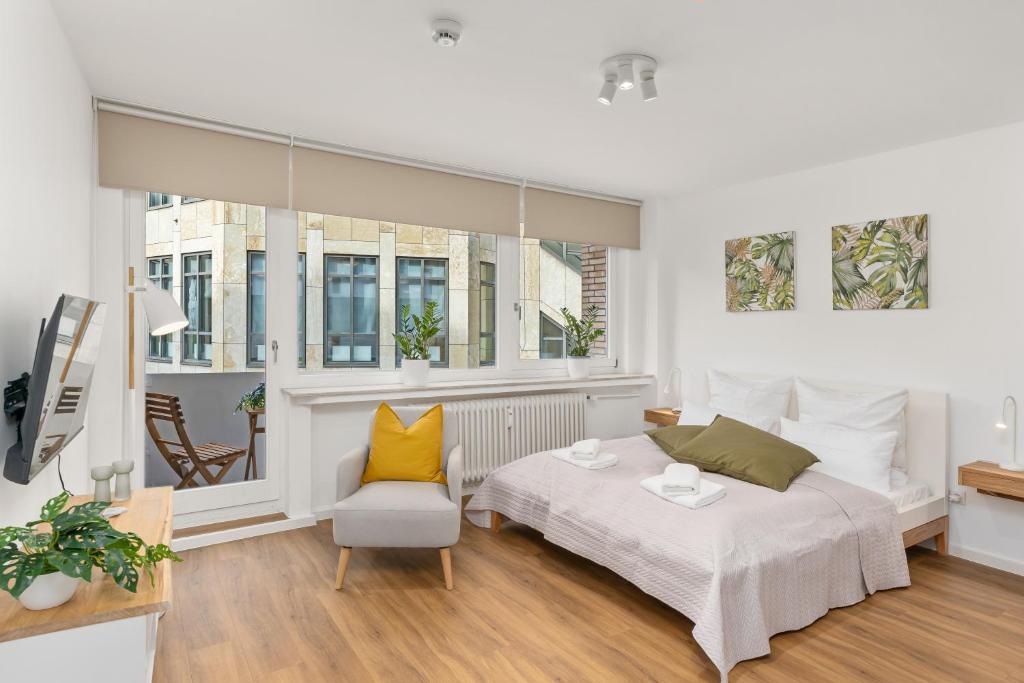 不莱梅Studio-Apartment im Stadtzentrum的卧室配有床、椅子和窗户。