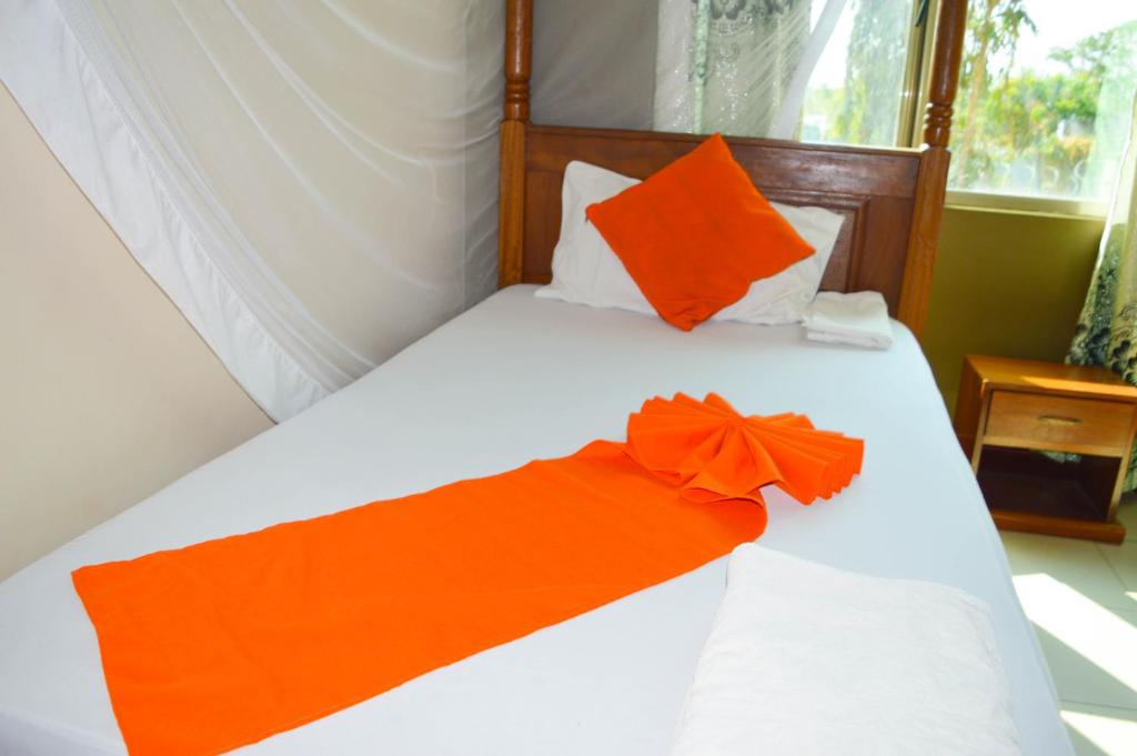 蒙巴萨Roma Stays - Elegant Apartment at Sunset Paradise with Swimming Pool & Restaurant的一张白色的床,上面有橙色的弓