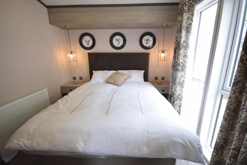 Merston2 Bedroom Villa - Lakeside Holiday Park的一间卧室设有一张大床,墙上挂有三个钟。