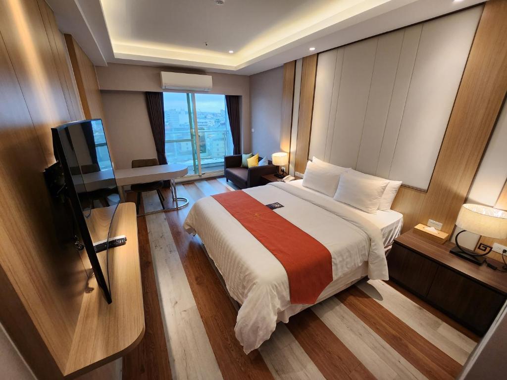 中坜宾利酒店的一间卧室配有一张床、一张书桌和一台电视