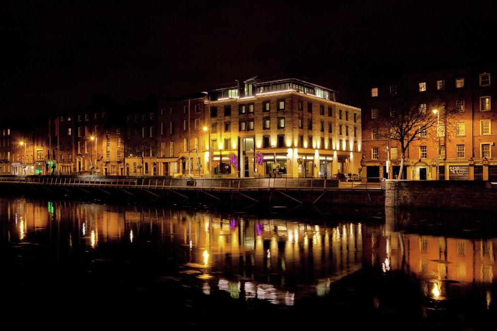 都柏林The Morrison Dublin, Curio Collection by Hilton的夜间在河边的一座有照明的建筑