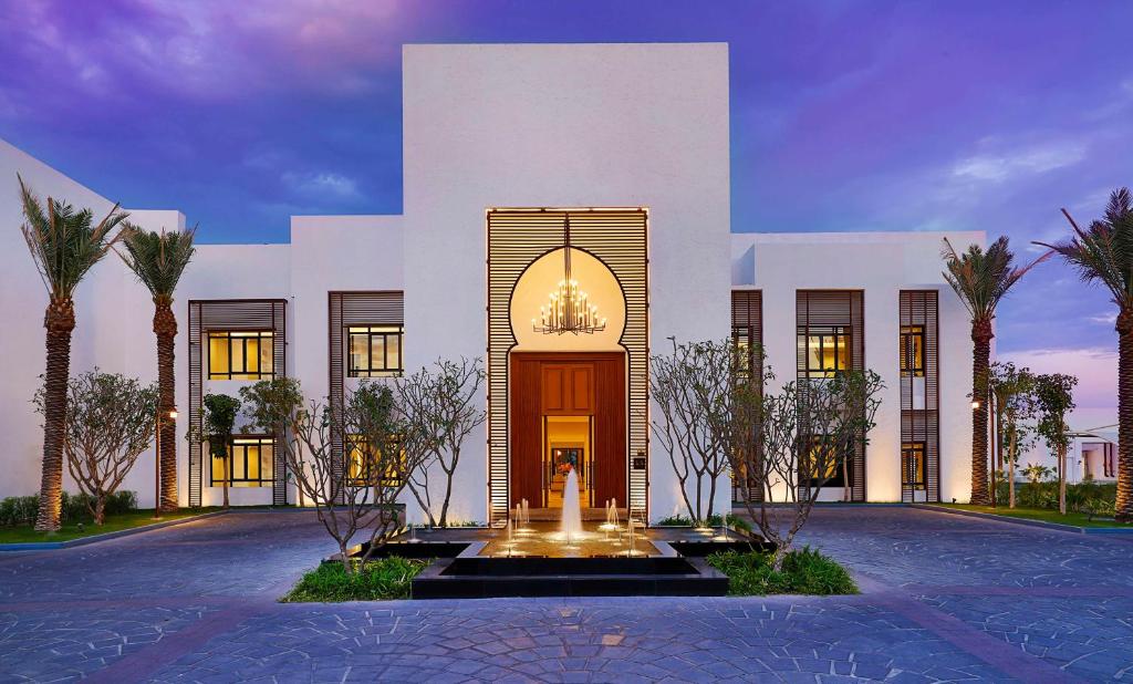 多哈Maysan Doha, LXR Hotels & Resorts的一座白色的大建筑,前面有一个喷泉