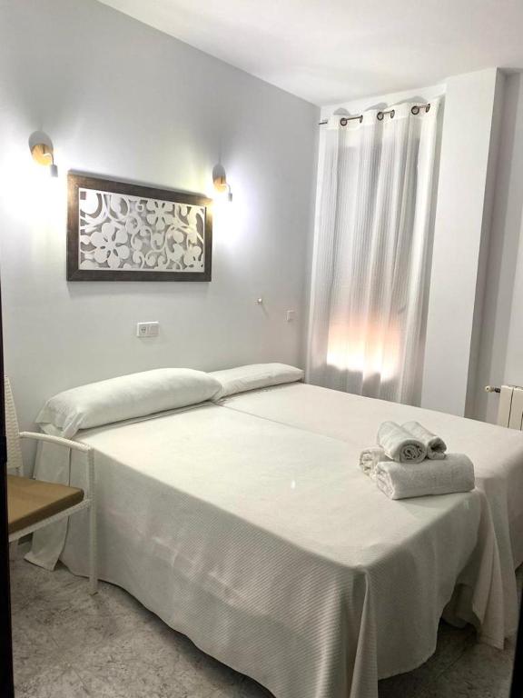 La ZarzaHostal Casa López的卧室配有白色的床和毛巾
