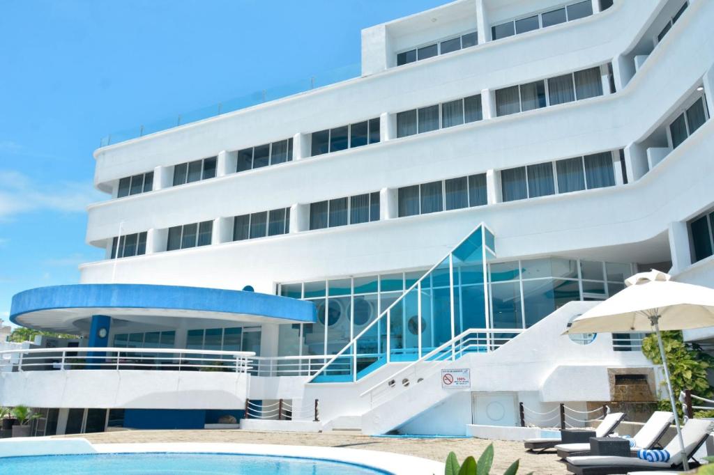 PampatarAquarius Hotel Boutique的一座白色的大建筑,前面设有一个游泳池