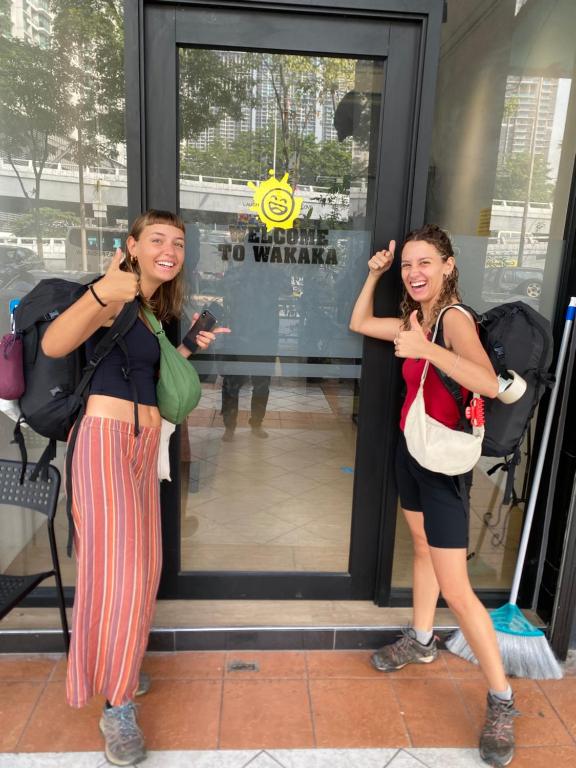 吉隆坡Wakaka Hostel的两个女孩站在商店外面