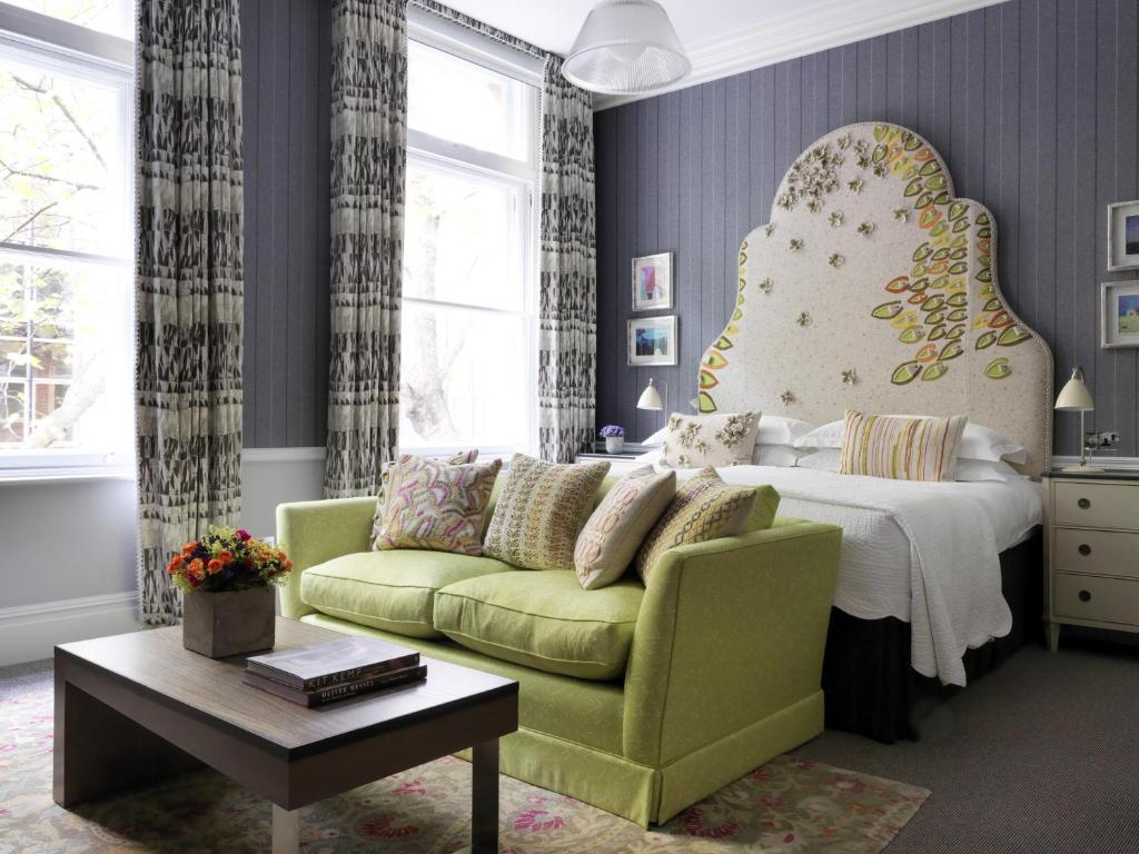 伦敦考文特花园酒店的一间卧室配有一张床和一张绿色沙发