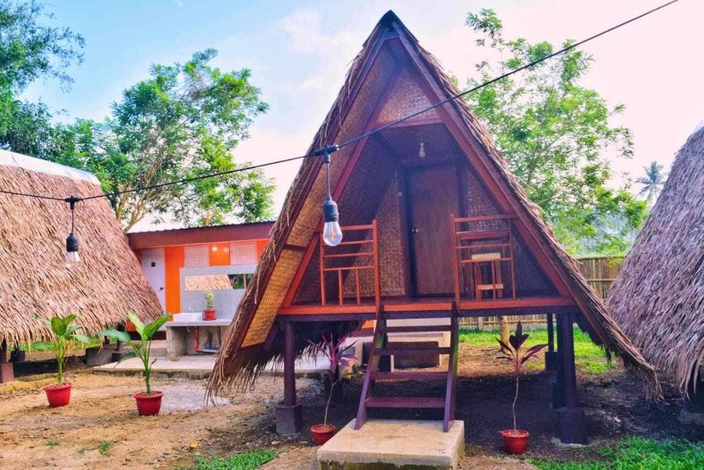 爱妮岛HIRAYA Camp Site - FREE use of SCOOTER for NIPA HUTS的茅草屋顶和双面板的小房子