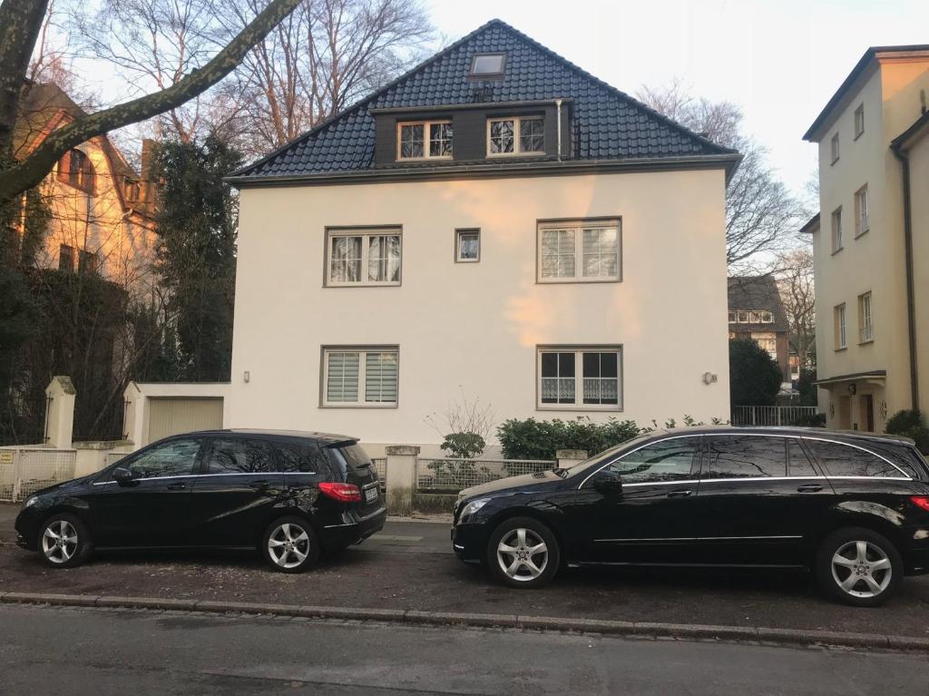 奥伯豪森Erdgeschoss Apartment am Park im Theaterviertel in Oberhausen的两辆汽车停在白色房子前面