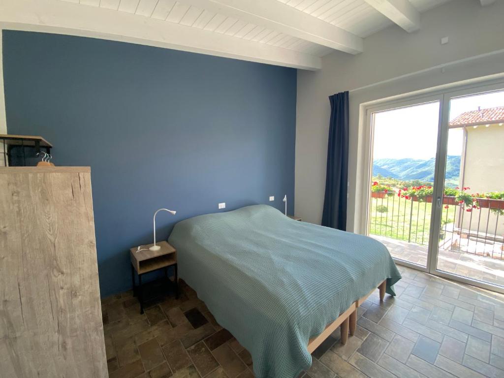 RoncovetroFuoridicampo的蓝色的卧室设有床和大窗户