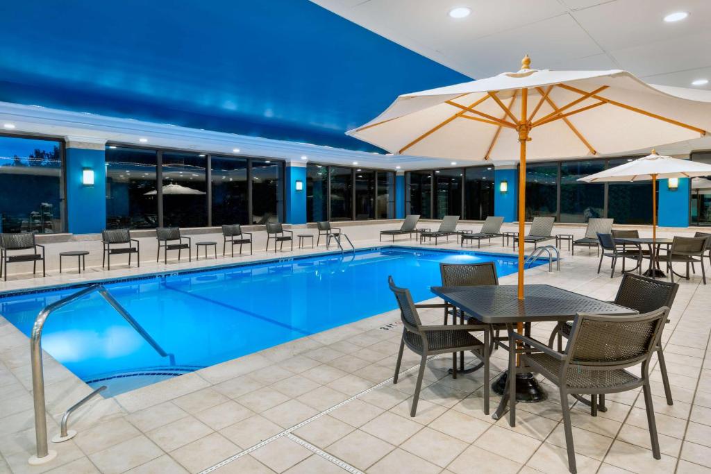 温莎洛克斯哈特福德机场汉普顿酒店的一个带桌椅和遮阳伞的游泳池
