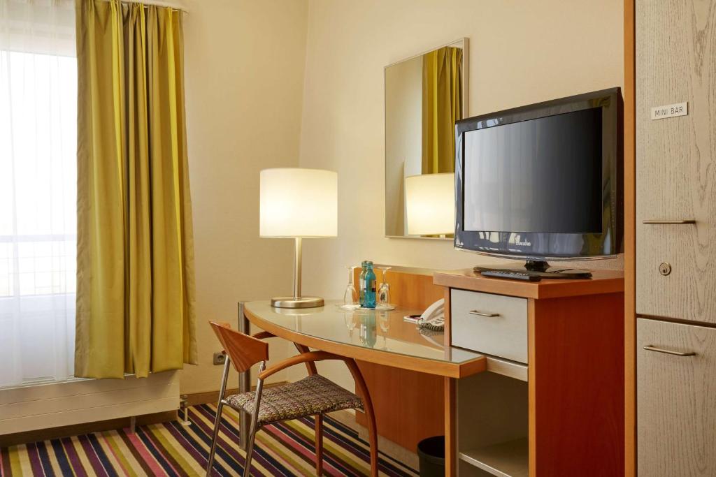 许尔特胡尔特 - 科隆华美达大酒店的酒店客房设有一张书桌,电视