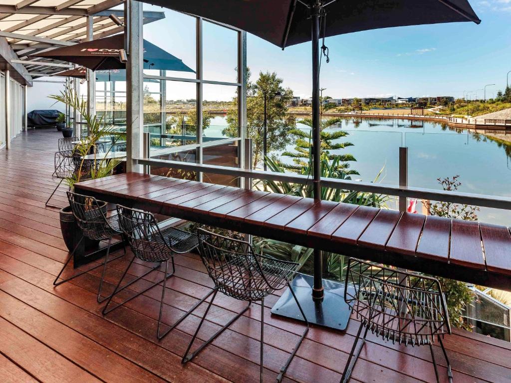 卡瓦纳华特斯Mercure Sunshine Coast Kawana Waters的阳台配有木桌和椅子,游泳池