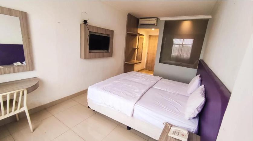 SukaramiBelvena Makati Hotel的一间卧室配有一张床、一张书桌和一台电视