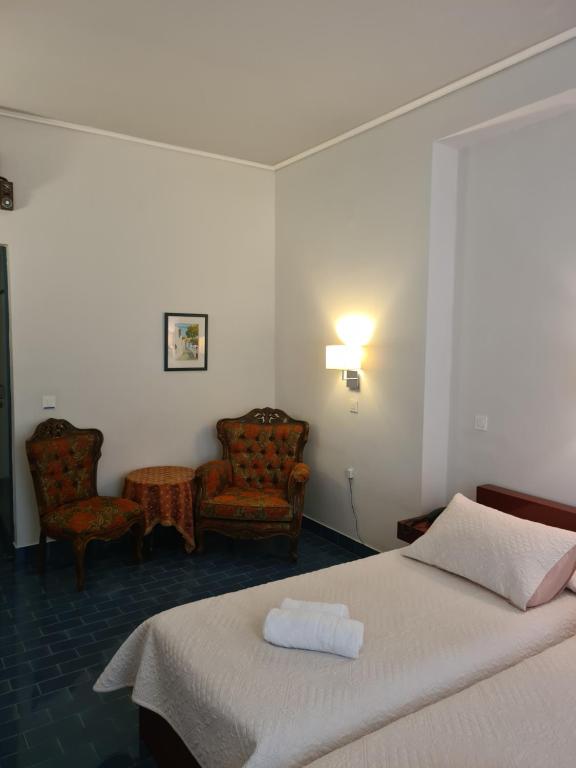 伊兹拉Greco Hotel的酒店客房,配有一张床和两把椅子
