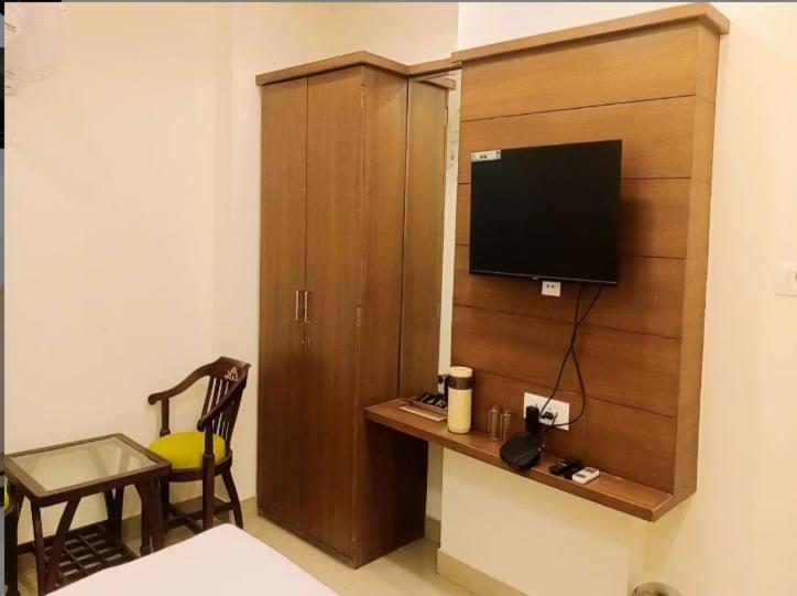 瓜廖尔Hotel Sakshi Inn Rooms and Restaurant的一间卧室配有一个木柜,里面配有电视