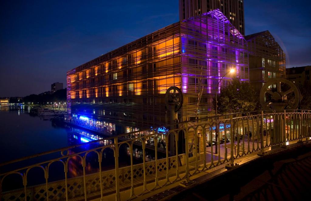 巴黎快捷假日巴黎加纳尔德拉维莱特酒店的河边一座紫色灯的建筑