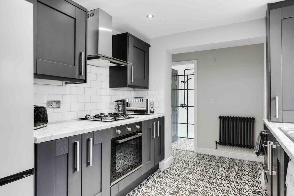 利物浦4 bedroom stylish home central location的厨房配有黑色橱柜和炉灶烤箱。