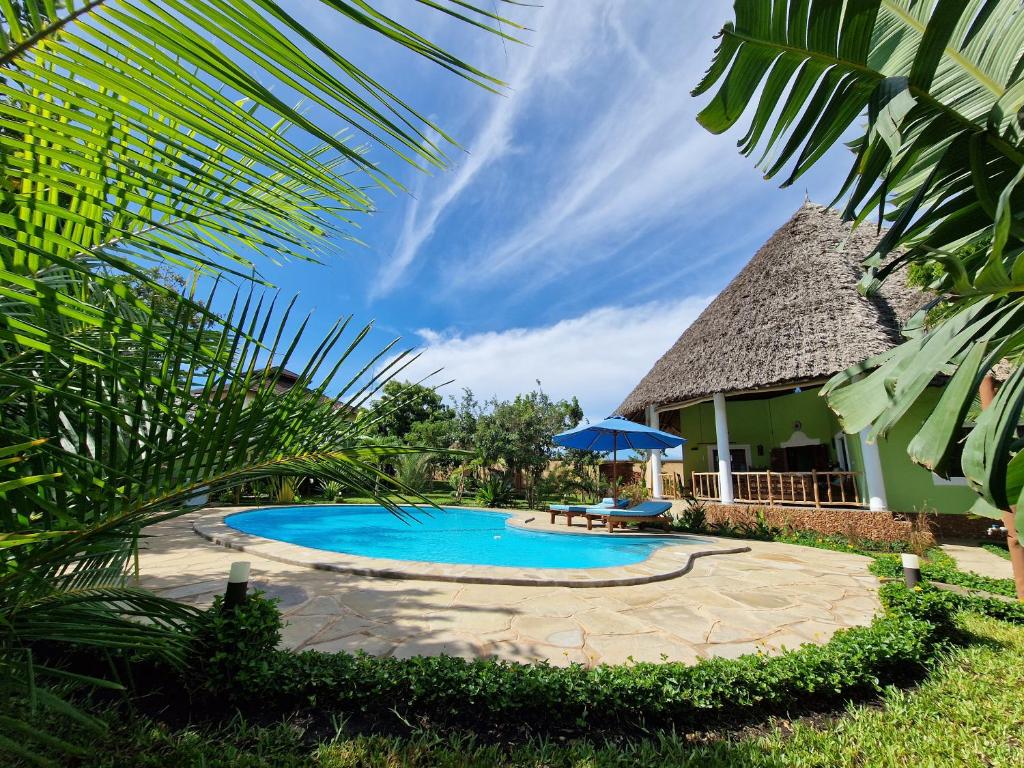 迪亚尼海滩Paradiesische Villa Maisha Mazuri mit Pool. Terrasse und Personal的一座带遮阳伞的房屋前的游泳池
