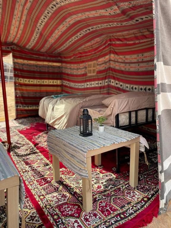 Authentic Desert Camp的帐篷内带桌子和床的房间