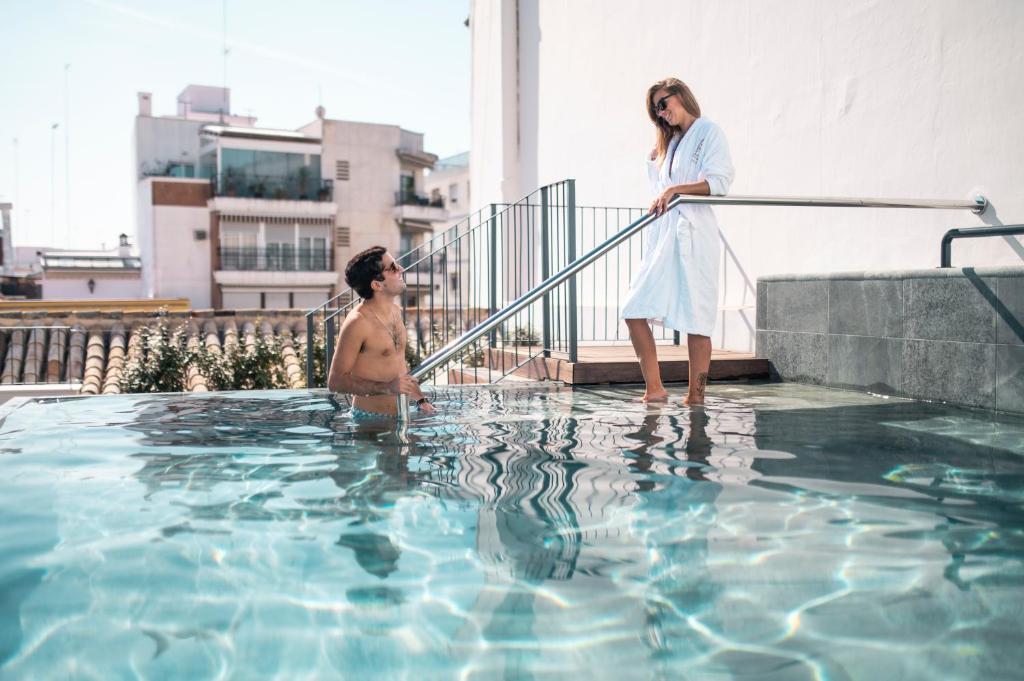 塞维利亚Legado Magdalena Hotel的站在游泳池中的男女