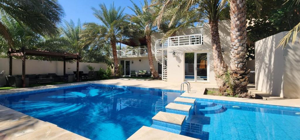 Bawsharفيلا مسقط - Muscat Villa的棕榈树屋前的游泳池