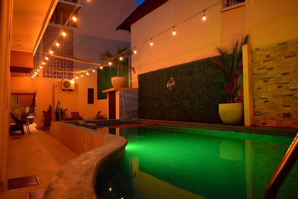 蓬塔雷纳斯Hotel Cabinas Midey的一座带绿水的游泳池,位于一座带灯光的房屋内