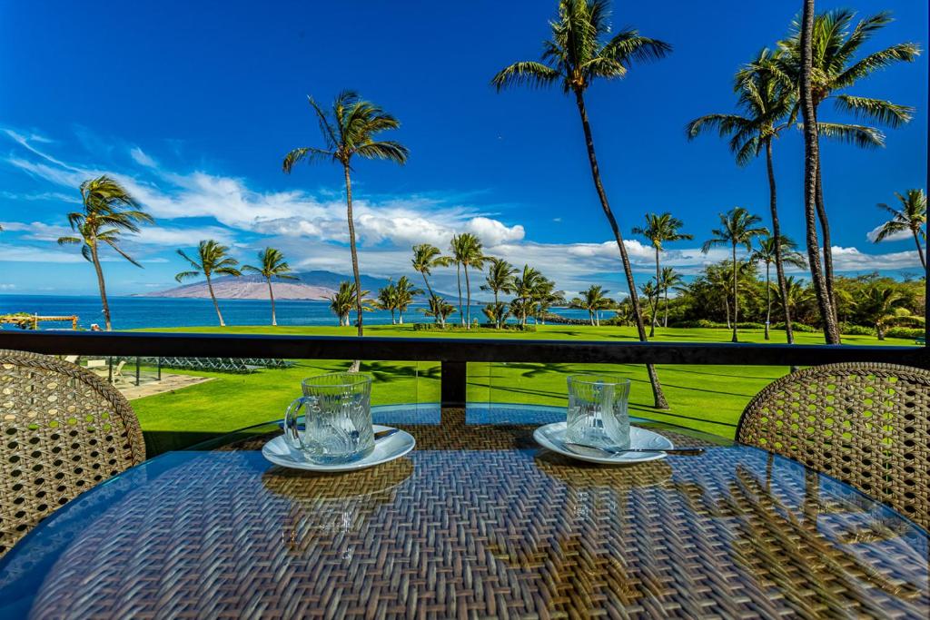 维雷亚Enjoy Your Oceanside Dream at Kihei Surfside的一张桌子,享有大海和棕榈树的景色