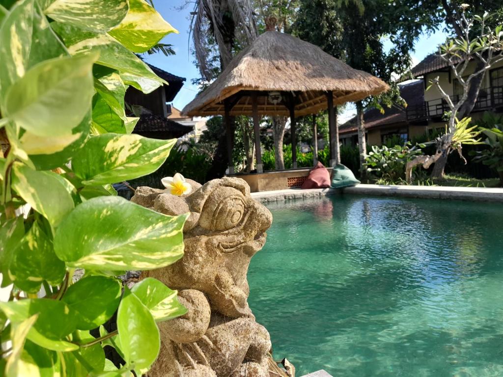 沙努尔普里库塔莱斯塔里旅馆的一座带雕像的度假游泳池,位于一座建筑旁边
