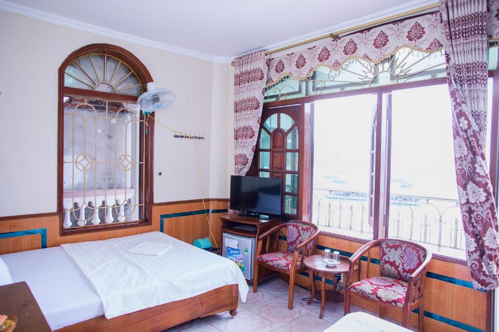 吉婆岛Tra My Hotel (Khách sạn Trà My)的一间卧室设有一张床、一台电视和两个窗户。