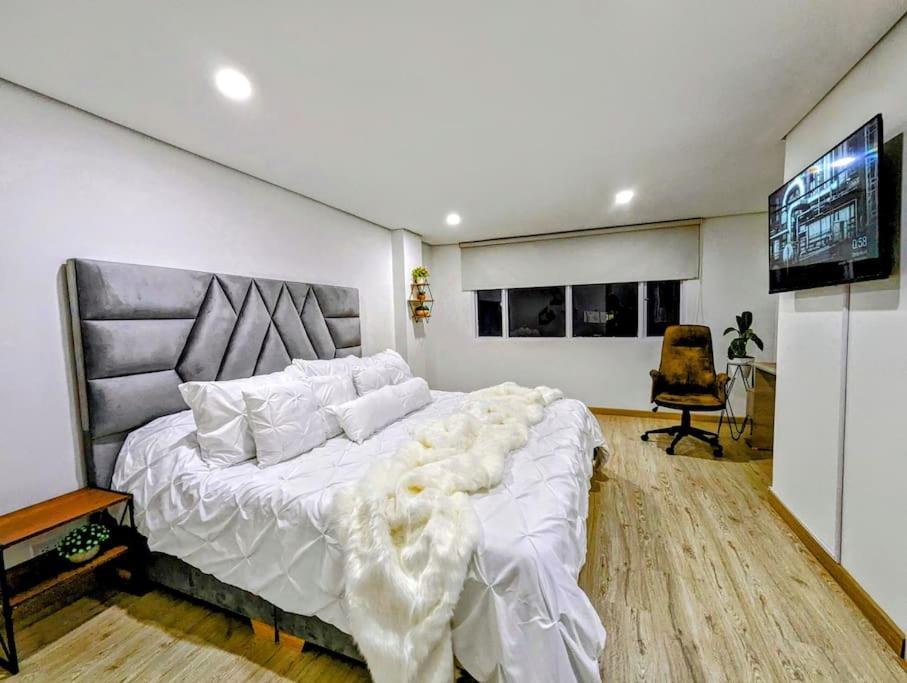 波哥大CHARMING APARTMENT IN CHICO RESERVED, 93 PARK, ZONE T!的卧室配有一张白色大床和一台平面电视。