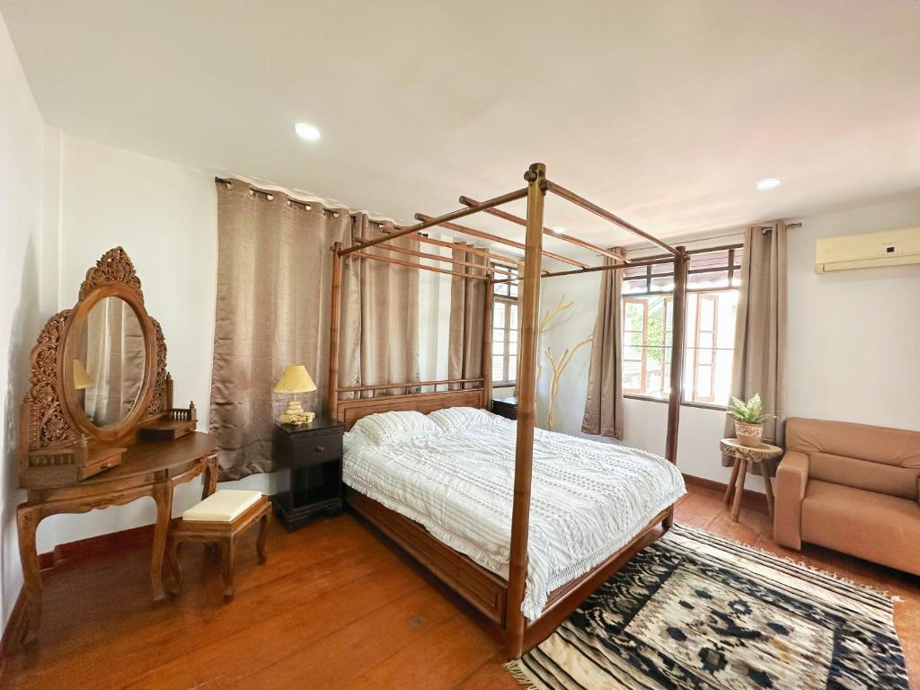 清迈An‘s Home的一间卧室配有天蓬床、一张桌子和一张沙发