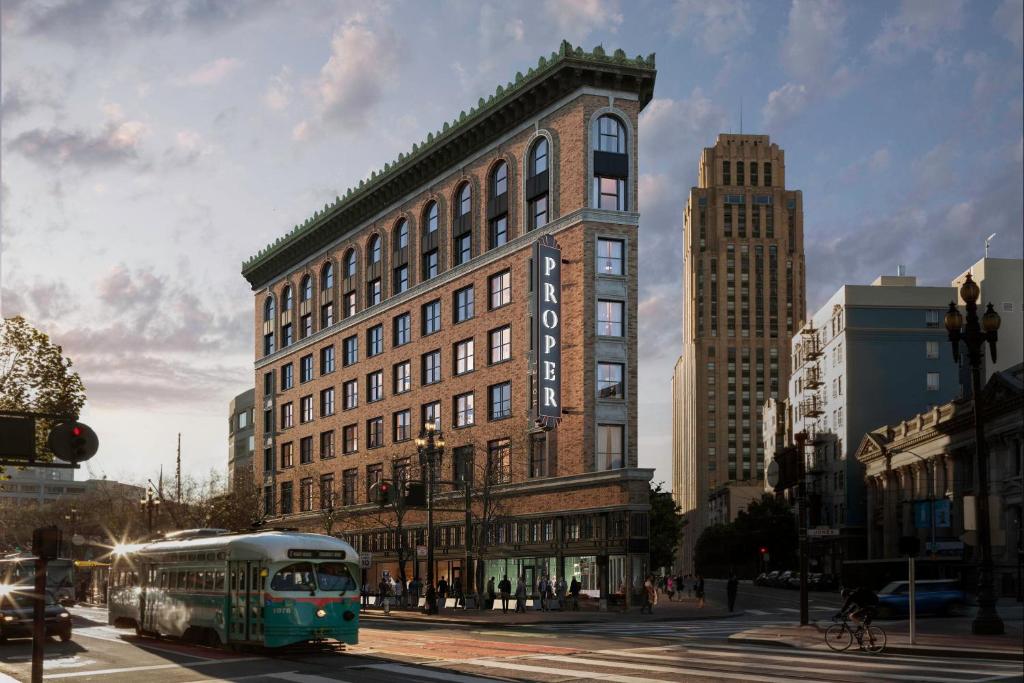 旧金山San Francisco Proper Hotel, a Member of Design Hotels的一辆公共汽车在建筑物前的街道上行驶
