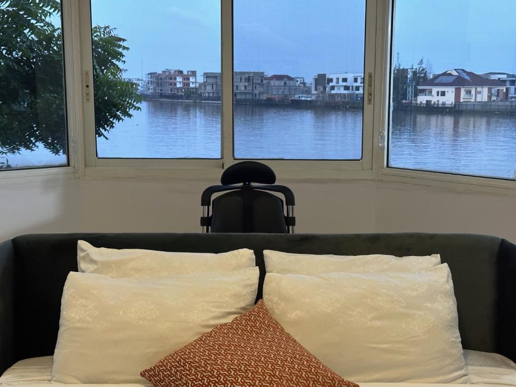 拉各斯Guided Hospitality - Luxury Accommodations的三扇窗户前的沙发及两个枕头