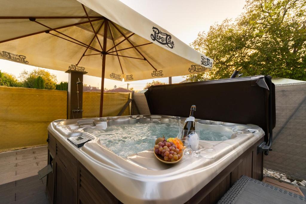 杜瑙保陶伊Szelidi Apartmanok的热水浴池配有一碗水果和一把遮阳伞
