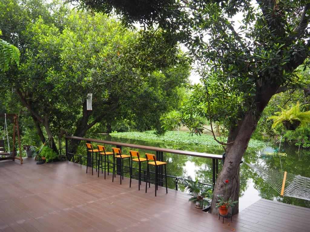 大城Banmai87 Guest House บ้านไม้87 เกสต์เฮ้าส์的一个带椅子的甲板,一棵树和水