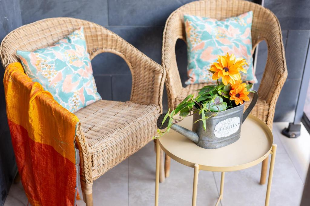 瓜尔达马尔·德尔·塞古拉Fidalsa Enjoy Life的两把柳条椅和一张带花瓶的桌子