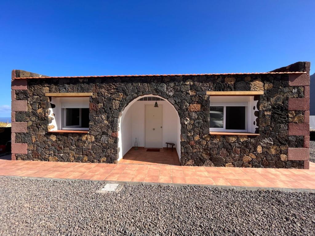 弗龙特拉Casa Valentina El Hierro的一座石制建筑,设有白色门和两扇窗户