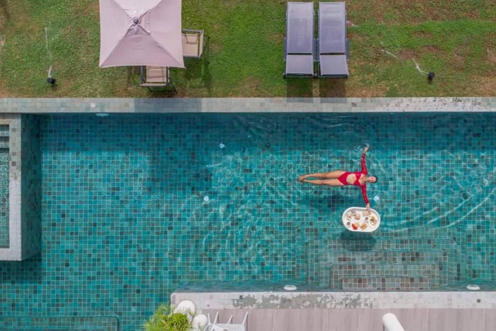 南芭堤雅Viva Montane Hotel Pattaya的游泳池,水中有一个女人坐在椅子上