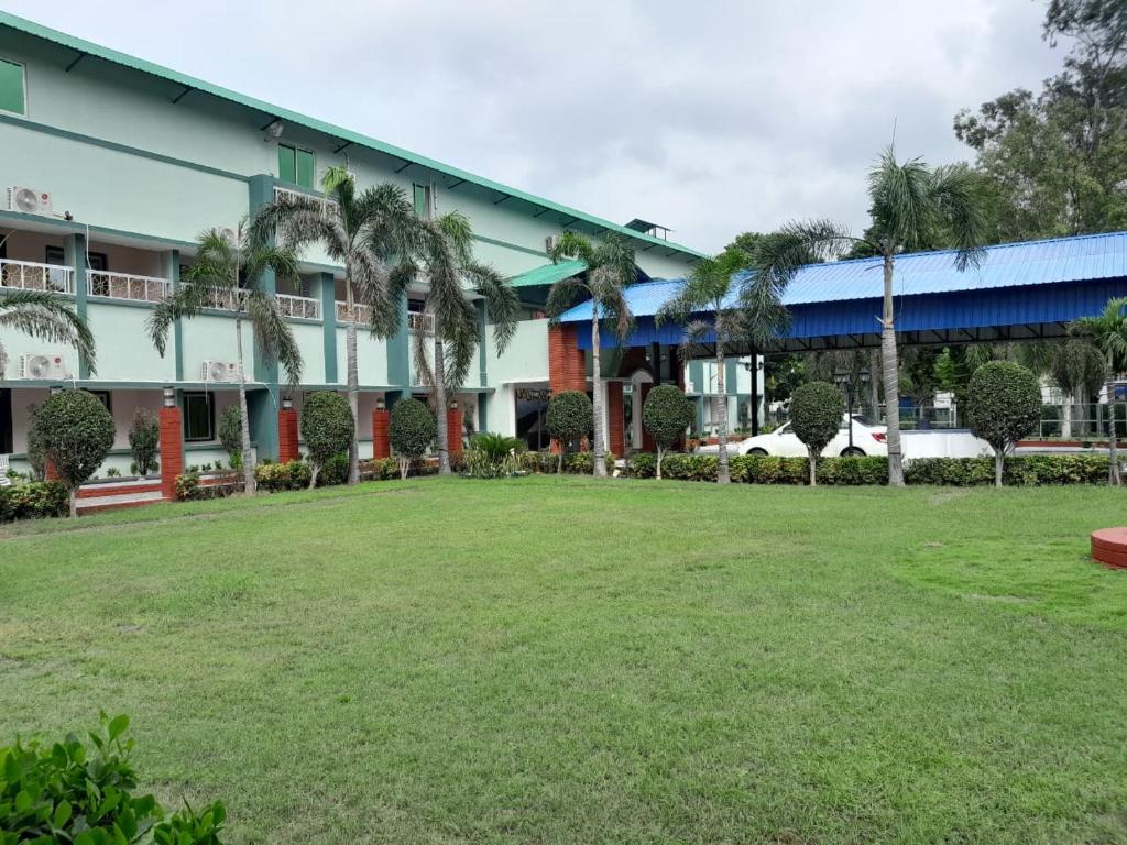 王舍城Aarunya Hotel And Resort的庭院前有棕榈树的建筑