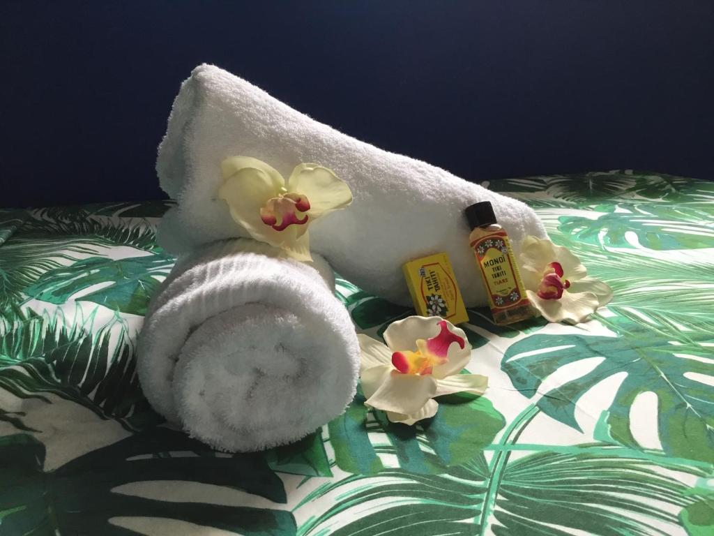 帕皮提Belle Maison F3的床上的毛巾、肥皂和鲜花