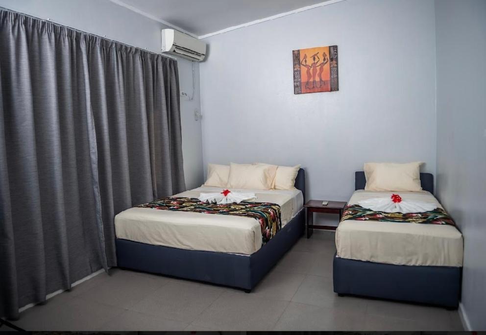 苏瓦Yatulau Hotel and Conference的一间卧室设有两张床,窗户配有窗帘
