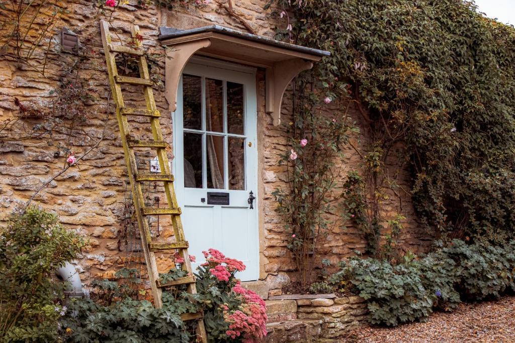 约克Quirky Tiny Home in York Moors的靠在石屋上的梯子,石屋上有一扇白色的门