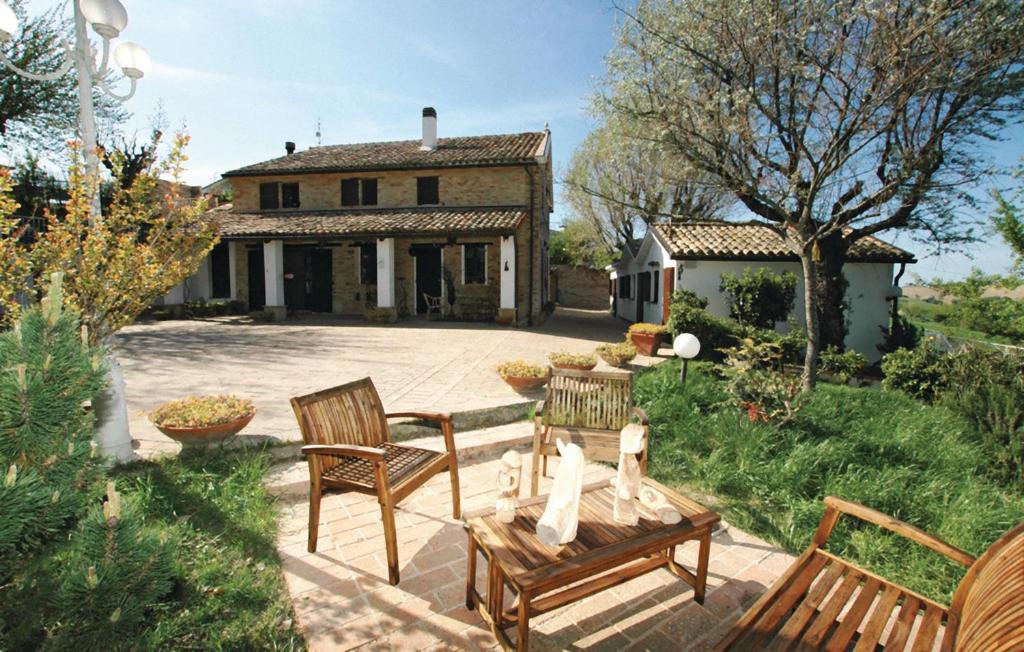 西尼加利亚Casale Barbagianni的房屋前设有带2把椅子和1张桌子的庭院。