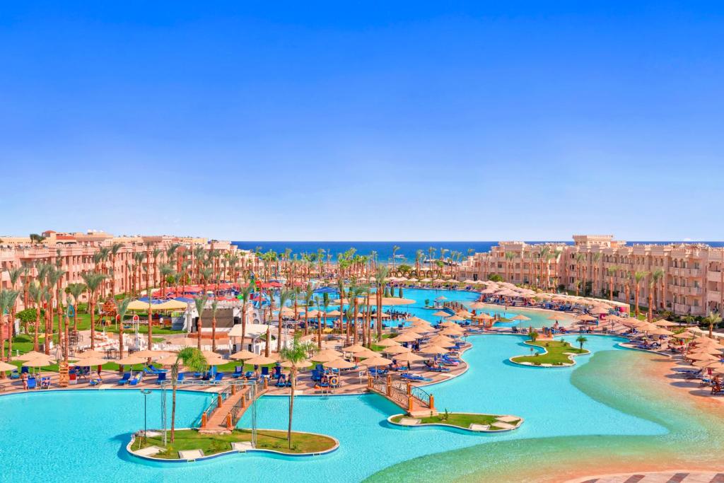 赫尔格达Pickalbatros Palace - Aqua Park Hurghada的享有带游泳池和遮阳伞的度假村的空中景致