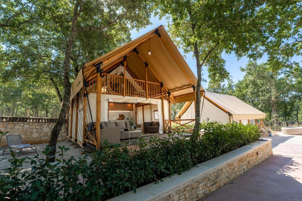 BašićiBanki Green Istrian Village - Holiday Homes & Glamping Tents的树林里围着门廊的房子