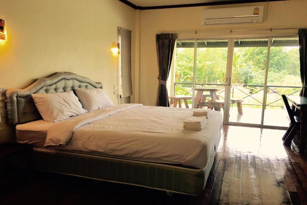 素叻萨布伊一流度假酒店的一间卧室设有一张大床和大窗户