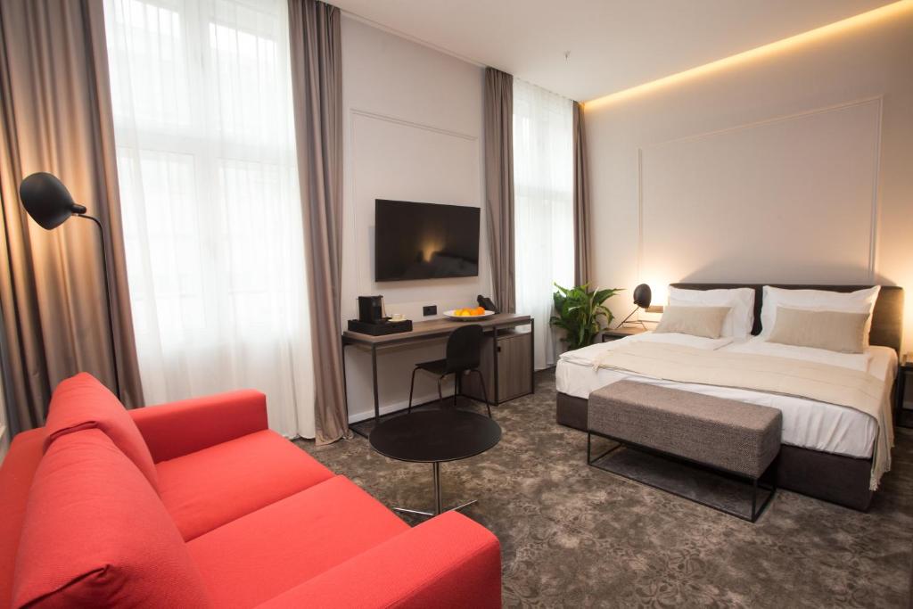 萨格勒布MANDA Heritage Hotel的酒店客房,配有一张床和一张红色的沙发