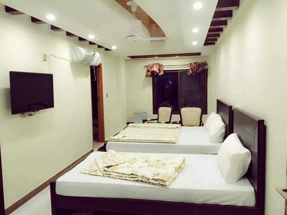 伊斯兰堡PAK HOTEL Islamabad的客房设有两张床、一台电视和一张桌子。