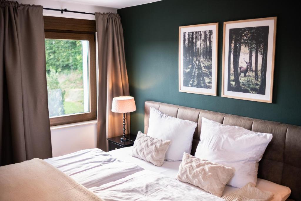 普吕姆Eifellodge - am roten Sandberg的卧室配有带枕头的床铺和窗户。